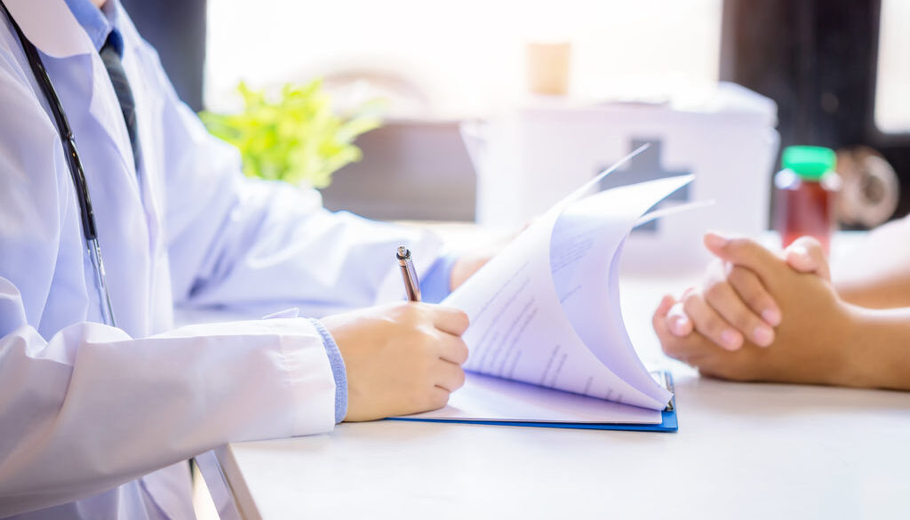 Doctor man consulting patient while filling up an application fo