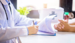 Doctor man consulting patient while filling up an application fo